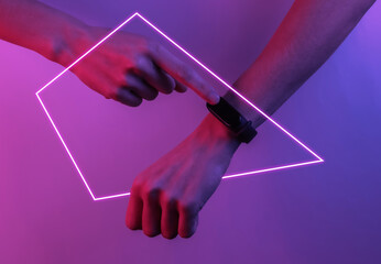 Female hand with a smart bracelet. Modern gadgets. Creative pop art pink blue neon color. Trendy...