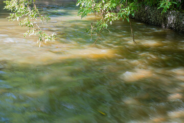 Background with a fast flowing mountain river surrounded by trees. Concept - mountain hiking and...