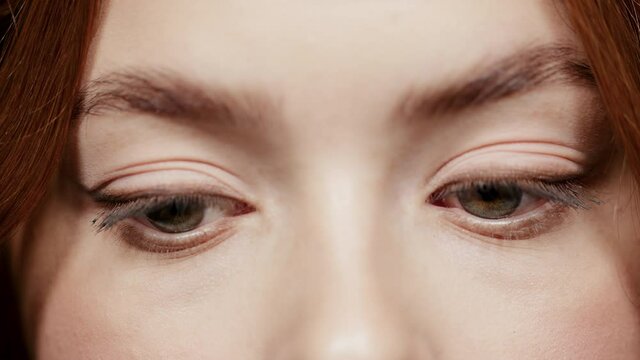 Gorgeous female grey eyes blinking indoors. Woman face on videotaping in atelier