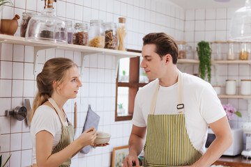 Obraz premium Happy & smiling attractive young cute caucasian couple in love enjoying cooking healthy salad in kitchen at home together. Happiness family of beautiful romantic married lover or marriage relationship