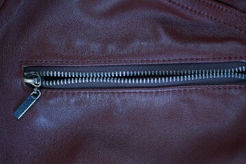 one open gray metal zip on the pocket of a leather brown jacket