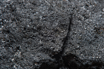 Blurred black background in soft focus with hard coal at high magnification. An image on the theme of geology and the extraction of minerals and natural fuels.