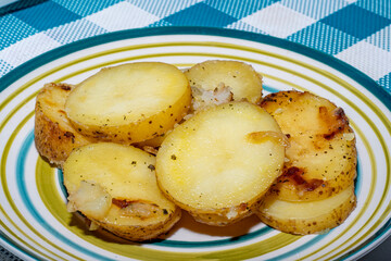 Hot baked potato slices with thin skinned potatoes on a plate. A simple and quick after-work meal for the worker and bachelor. Inexpensive food for poor people and farmers