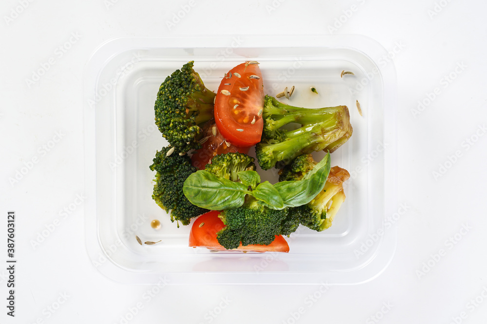 Wall mural grilled vegtables - broccoli, tomatoes with seeds in a lunch box. healthy lunch to go