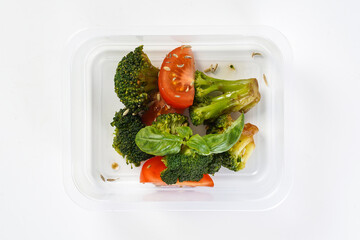 Grilled vegtables - broccoli, tomatoes with seeds in a lunch box. Healthy lunch to go