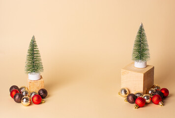 New year creative concept. Two artificial Christmas trees on wooden cubes and red, golden, brown Christmas decorations around on a beige background. Christmas background.Copy spase, space for text