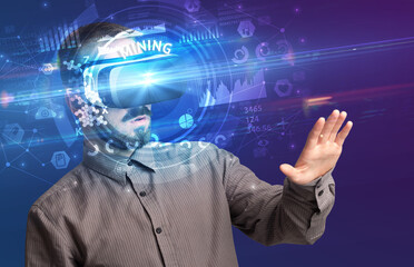 Businessman looking through Virtual Reality glasses with MINING inscription, innovative technology concept