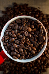 Coffee beans in the cup and on the table around the cup