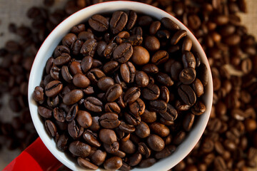 Coffee beans in the cup and on the table around the cup