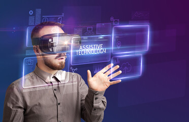 Businessman looking through Virtual Reality glasses with ASSISTIVE TECHNOLOGY inscription, new technology concept