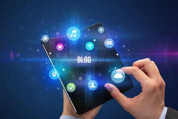 Businessman holding a foldable smartphone with BLOG inscription, social media concept