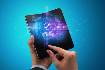 Businessman holding a foldable smartphone with INSURTECH inscription, new technology concept INTERNET OF THINGS