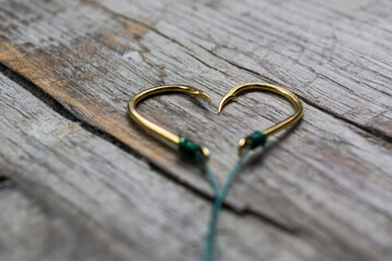 Fishing hooks set in the shape of a heart on a wooden background.