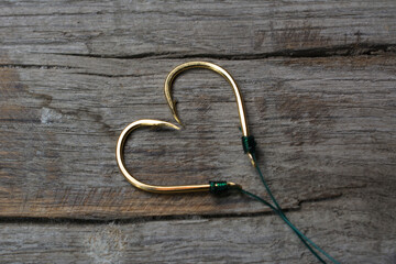 Fishing hooks set in the shape of a heart on a wooden background.