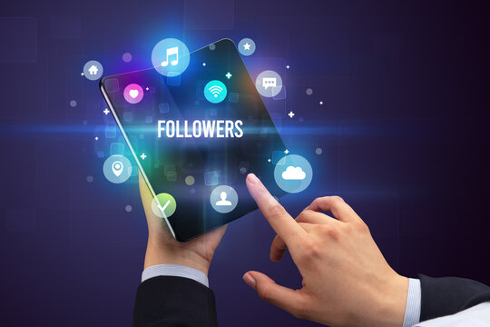 Businessman holding a foldable smartphone with FOLLOWERS inscription, social media concept