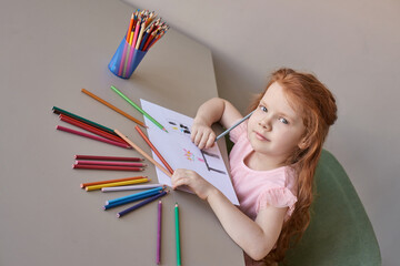 Little girl drawing. Closed Locking Exercise. Homemade routine. School lessons. Write pencil on piece of paper. Kindergarten study. Elementary preschool. Woman kid student. Thinking or dreaming