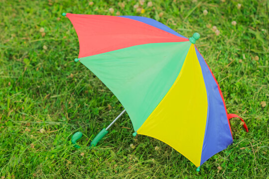 A colorful children's Umbrella on the green Lawn. The concept of a happy childhood.