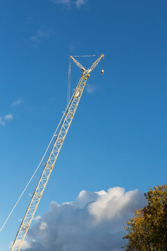 high yellow construction crane on a background of blue sky and white clouds
