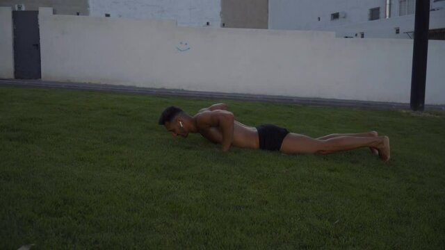 A young man doing calisthenic jumps in a park. Calisthenic