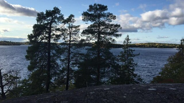 Nice view over a sea side at the Swedish lake M&auml;laren(Malar or Malaren). Cliffs and fir trees in front of the water. Some clouds in the background. J&auml;rf&auml;lla, Stockholm, Sweden.