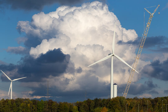 construction of a wind generator and power line on a background of of a dramatic cloudy sky and forest