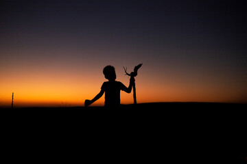 The silhouette of a young boy in the desert sunset