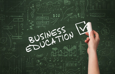 Hand drawing BUSINESS EDUCATION inscription with white chalk on blackboard, new business concept