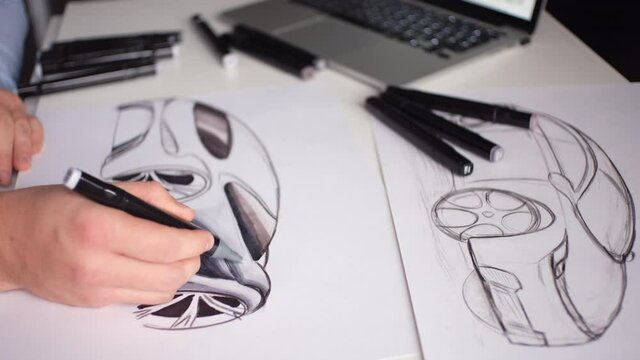 A man draws a design project for a future car at home