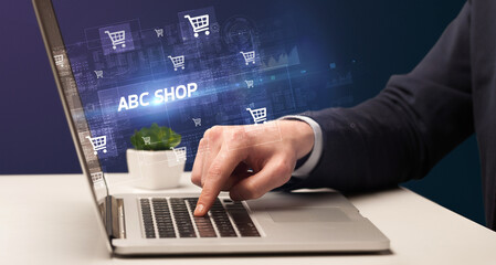 Businessman working on laptop with ABC SHOP inscription, online shopping concept