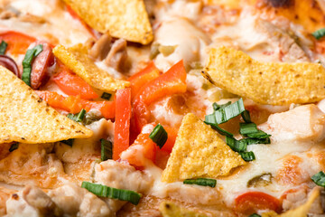 Close up view of delicious mexican pizza with cheese mozzarella , tomatoes, sausages, bacon, chicken and green onion. Top view