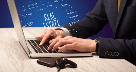 Businessman working on laptop with REAL ESTATE inscription, online shopping concept