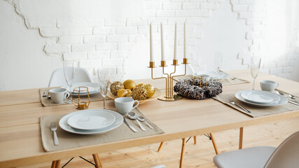 New Year's table setting. Christmas wreath, candles, tree. Beautiful festive interior