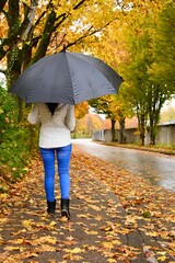 Young woman on the street with umbrella. Walk in the rain on autumn day.