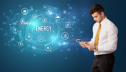 Businessman thinking in front of technology related icons and ENERGY inscription, modern technology concept