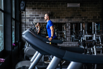 Fototapeta na wymiar Young man in sportswear running on treadmill at gym.