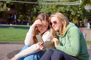 Two pretty girls, hipster girls, sisters using smartphone, close-up. Lifestyle and friendship concept