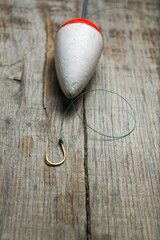 Hook and float prepared for fishing on a wooden background.