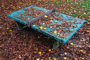 Tischtennisplatte auf Kinderspielplatz im Herbst, bedeckt mit herabgefallenen Blättern - Stockfoto