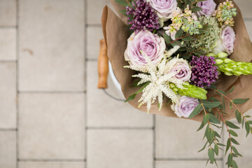 Top view of a beautiful bouquet of flowers on the background of paving slabs. A bucket of flowers outside. Selective focus