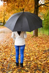 Young woman with black umbrella walking in the rain. autumn weather. 
