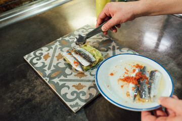 Chef placing fish on an avocado base and on a traditional Andalusian dish