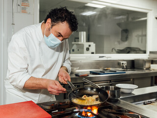 The male cook protects himself with a mask during his workday in the restaurant's kitchen.