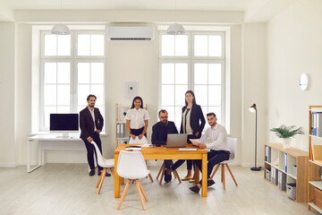 Team of business people discussing business ideas and smiling at the camera in the office.