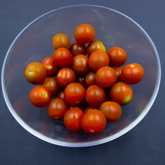 211 - Photograph of a glass salad bowl and cherry tomatoes on a dark background