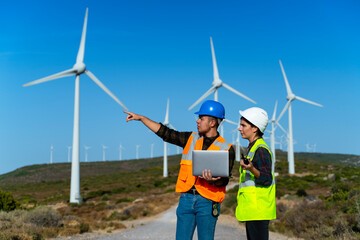 Technical businessman wearing protective face mask working in COVID-19 outbreak after novel coronavirus quarantine and lockdown standing with digital tablet pc on wind power energy station