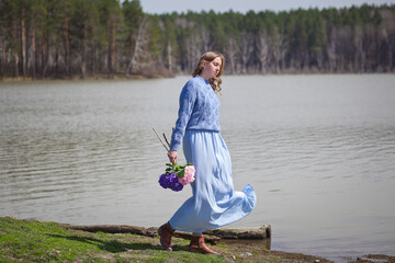 girl with a bouquet of hydrangeas walks on the shore, spring photo session