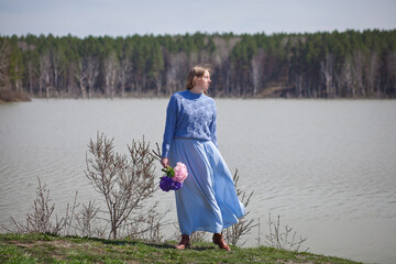 girl with a bouquet of hydrangeas walks on the shore, spring photo session