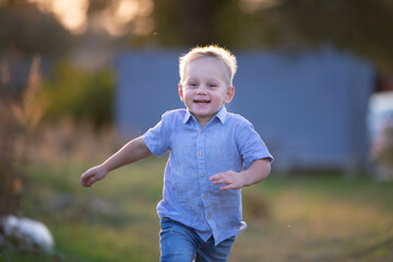 Handsome little boy with blond hair is playing in the field.