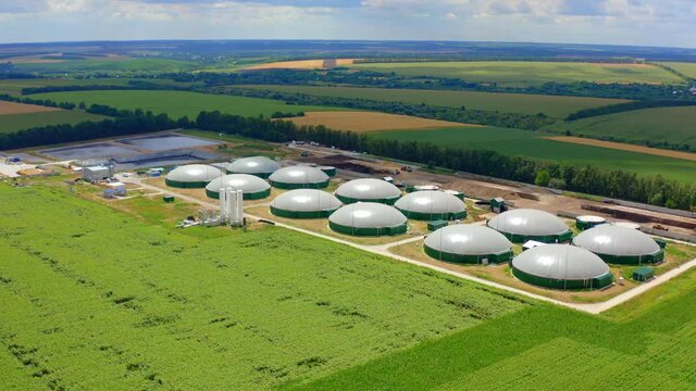 Biogas plant in bright summer day. Innovative agricultural farm for biomass production in green nature. Organic production of methane-containing gas in the countryside.