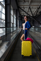 Caucasian woman on a horizontal escalator with a suitcase at the airport. A girl with pink luggage rides on a moving sidewalk